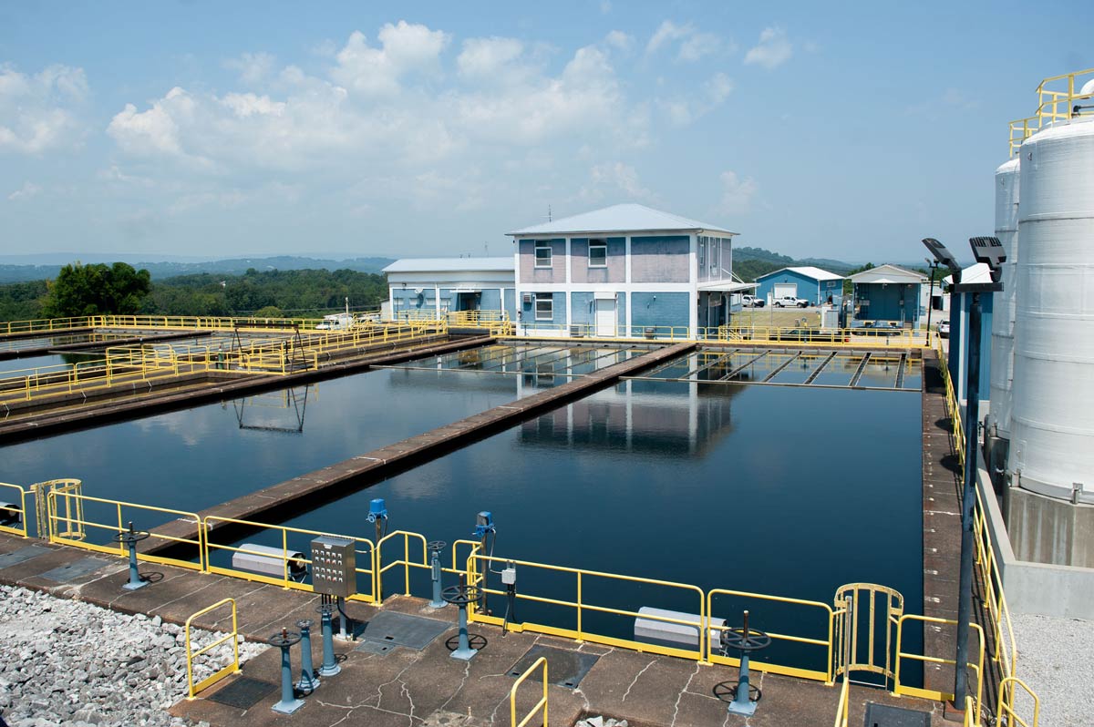 Water treatment basins at Eastside Utility District&rsquo;s treatment plant with yellow safety railings and plant buildings in the background.