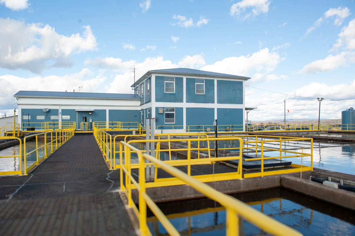 Walkways with yellow safety railings surrounding water treatment basins and plant buildings at Eastside Utility District&rsquo;s treatment facility