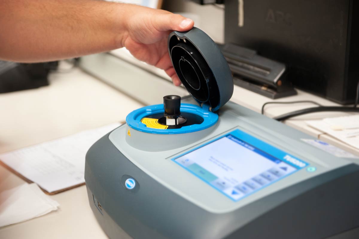Technician placing a sample into laboratory testing equipment used for water quality analysis